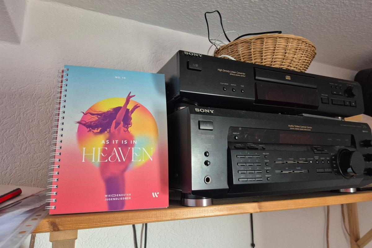 Songheft Wiedenester Liederbuch und eine Verstärkeranlage auf einem Regal